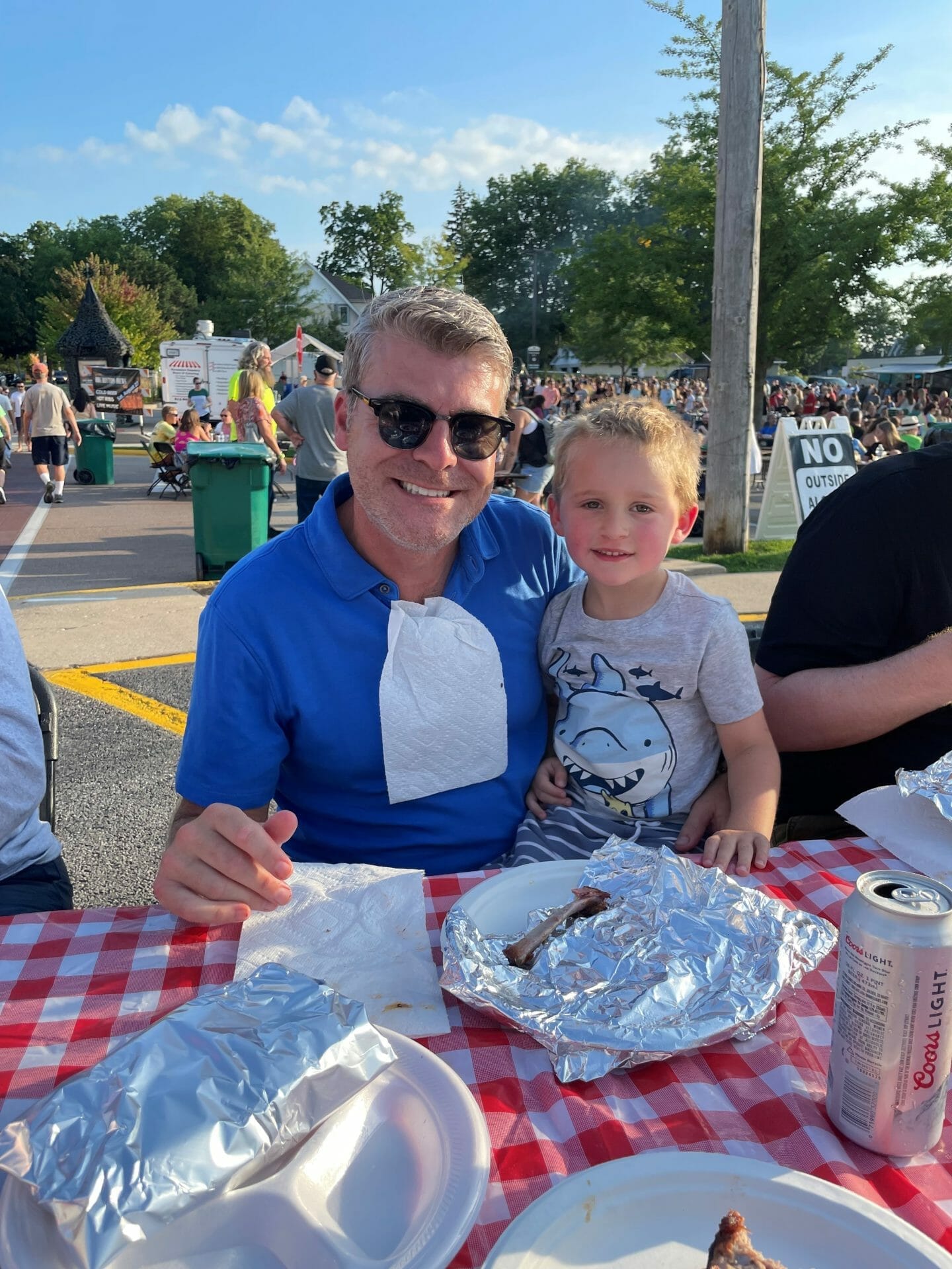 Man and a small child enjoying food outdoors.