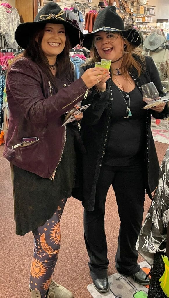 Two woman dressed and witches and smiling.